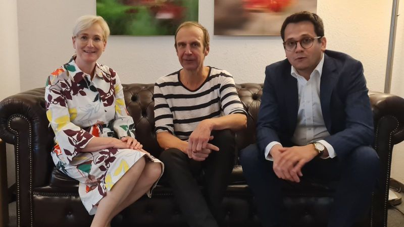 Petra Dassen-Housen,, Bürgermeisterin von Kerkrade, Moderator Torsten Knippertz und Benjamin Fadavian, Bürgermeister von Herzogenrath, sitzen gemeinsam auf einem Sofa.