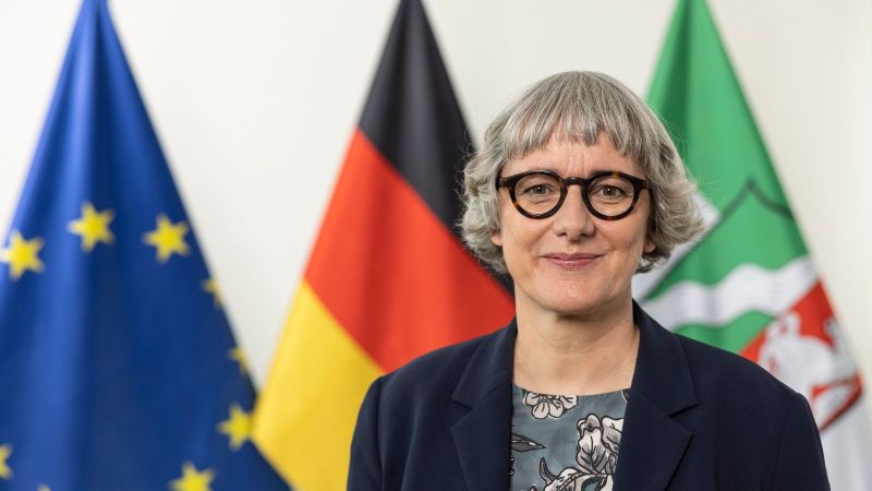 Staatssekretärin Silke Krebs vor den Flaggen von Europa, Deutschland und NRW