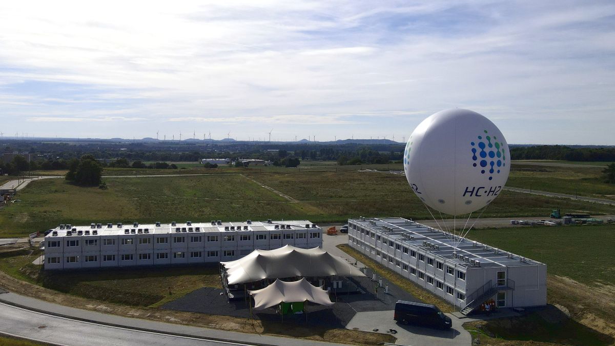 Container des Instituts für nachhaltige Wasserstoffwirtschaft neben dem Ort, an dem die neuen Gebäude entstehen sollen. Auf dem Dach eines Containers ein großer Ballon mit dem Logo des HC H2 anlässlich der Eröffnung.